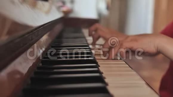 一个七岁的男孩在家弹钢琴一个男孩的手特写视频的预览图