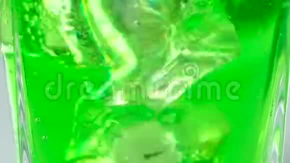 冰块漂浮在装有绿色碳酸鸡尾酒的玻璃杯中大型射击视频的预览图