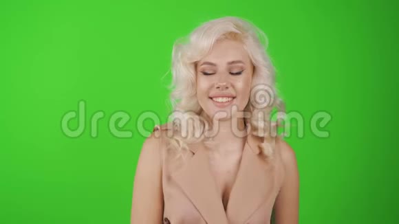 性感金发女人的肖像完美的身体和大胸摆在绿色工作室的背景上视频的预览图