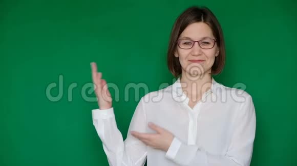 戴着眼镜的美丽微笑的女人绿色屏幕上的白色衬衫指向右边Chroma键视频的预览图