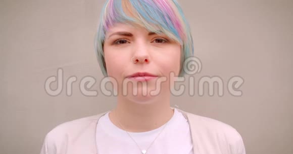 一位年轻时尚的白种人女性染着头发在户外看着摄像机墙上挂着一幅特写照片视频的预览图