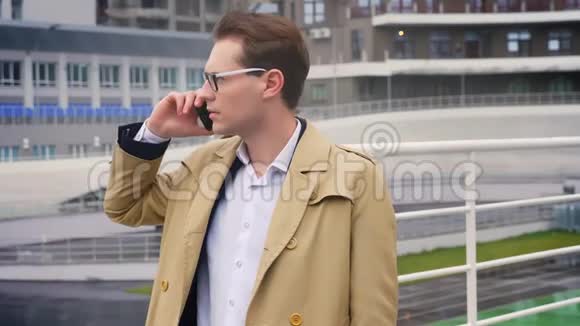 漂亮的白种人青年男子在一个严肃而集中的体育场旁通过电话交谈视频的预览图