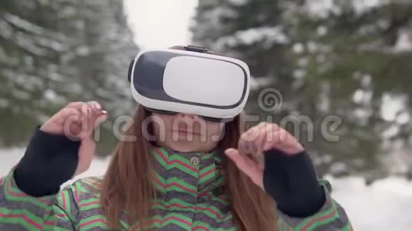 一个年轻的女人在雪地森林里的街道上使用电子虚拟现实眼镜慢动作视频的预览图