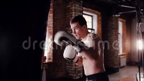 一名男子拳击手在明亮的健身房里用拳击袋训练视频的预览图