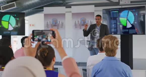女观众在商务会议上用智能手机拍摄视频的预览图