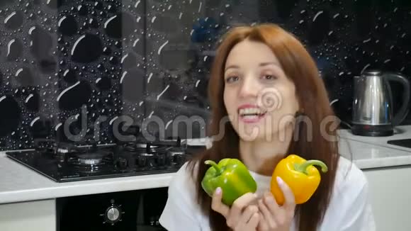 年轻的成年女孩在厨房准备食物前玩着黄色和绿色的甜椒健康的生活方式和视频的预览图