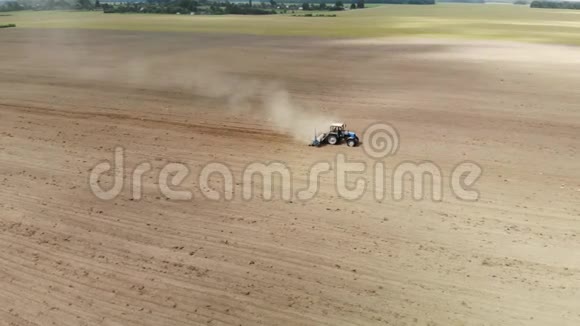 一个农民在蓝色拖拉机上带着播种机在干燥的沙质土壤中播种视频的预览图