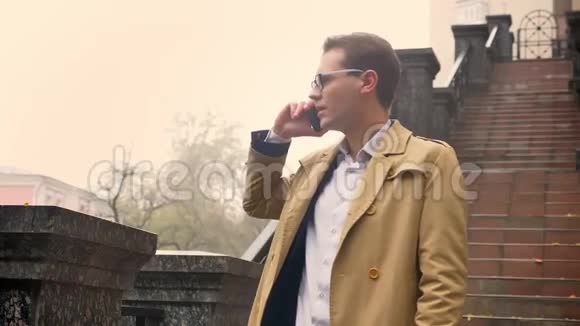 漂亮的白种人男人在电话里说话表情严肃站在楼梯旁边的公园里视频的预览图
