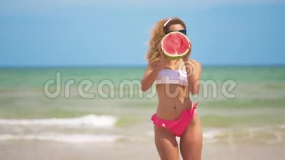 跳舞的女孩在美丽的大海的背景上有一个半多汁的西瓜视频的预览图