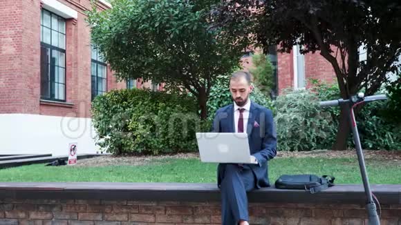 穿着西装的经理在外面用笔记本电脑工作视频的预览图