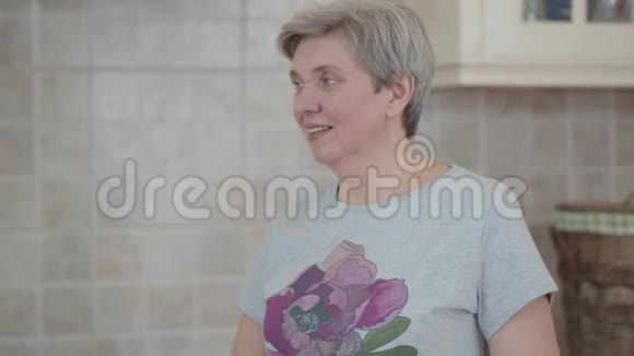 成熟的白发女人站在厨房里说话的肖像视频的预览图