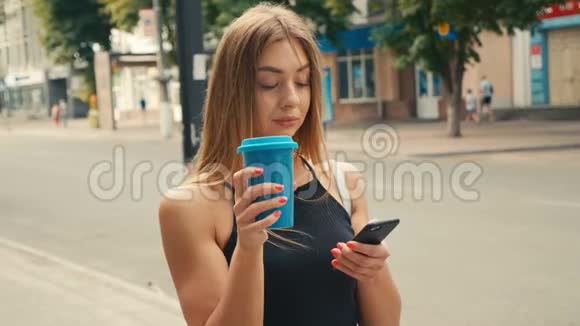 漂亮的年轻女性浅棕色头发使用智能手机在市中心喝咖啡视频的预览图