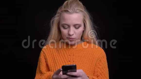 特写镜头拍摄年轻漂亮的白种人女性在手机上发短信在镜头前欢快地微笑视频的预览图