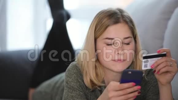 女人在家里的沙发上用智能手机和信用卡买东西视频的预览图