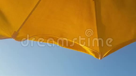 夏天海滩上的黄色伞顶在蓝天上视频的预览图