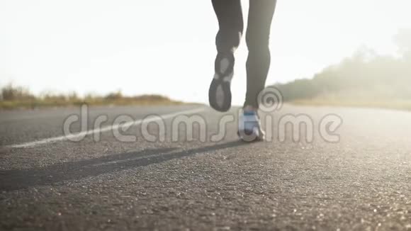 年轻的健身运动女子在日落时在路上跑步运动员跑脚在路上跑动作慢视频的预览图
