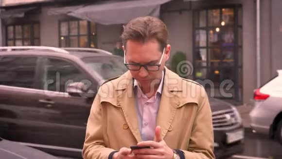 一位成年白种人的特写镜头看着电话因为站在街上的好消息而兴奋起来视频的预览图