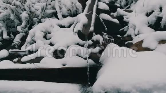 大雪干净透明的山水流顺着木沟流入特殊的水槽视频的预览图