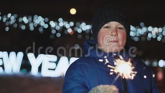 街上的男孩除夕他拿着一个火花挥动它视频的预览图