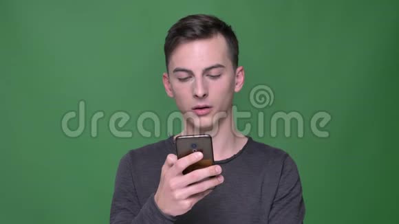 年轻英俊的白种人男性手机短信特写镜头背景与绿色隔离视频的预览图