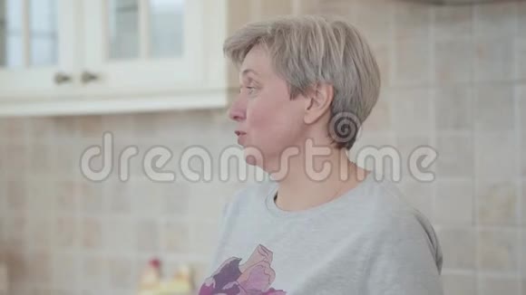 一个成年白发女人站在厨房里说话的肖像视频的预览图
