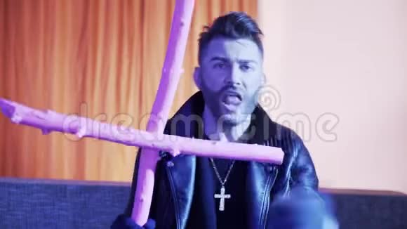 穿着皮夹克的帅哥抱着粉红十字架在沙发上唱歌跳舞视频的预览图