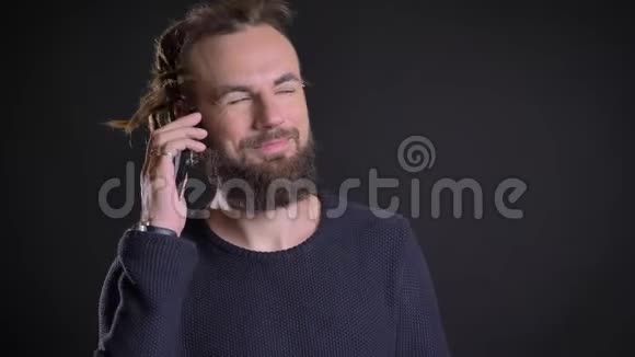 一个中年白种人长着可怕的长发在黑色背景下用手机讲话视频的预览图