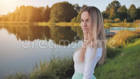 湖背景上一个17岁金发女孩的肖像视频的预览图