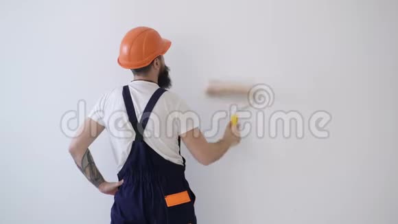 戴安全帽的工人在粉刷墙壁画家用油漆辊粉刷墙壁的后视图壁画概念视频的预览图