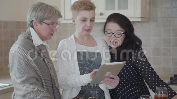 三位成熟的女友正在平板电脑上看一些有趣的东西正在积极讨论成年女性视频的预览图