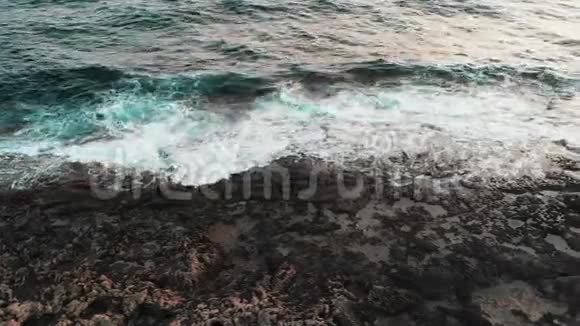 无人机俯瞰海岸黑色岩石海滩和美丽的巨浪在风暴中撞击悬崖视频的预览图