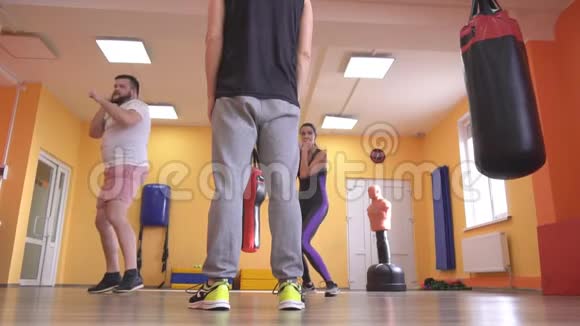一辆拳击教练训练一个男人和一个女孩在健身房里那里挂着拳击袋动作缓慢视频的预览图