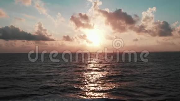 美丽的粉红色日落令人难以置信的阳光和巨大的海浪与岩石碰撞创造白色泡沫和视频的预览图