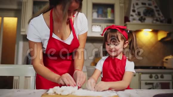 幸福的家庭在厨房里妈妈和女儿在厨房里玩面粉玩得开心在厨房里塑造馅饼视频的预览图