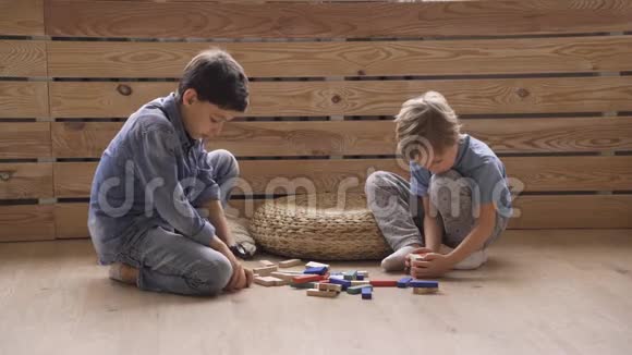 两个男孩的兄弟正在用坐在地板上的木块建造一座塔视频的预览图