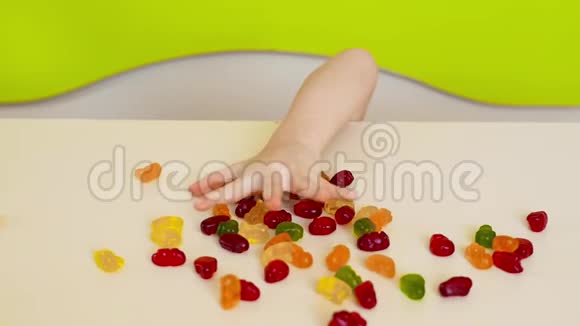 孩子们的手从桌子下面伸出来拿着鲜亮的水果糖快乐无名的孩子吃糖果什锦的视频的预览图
