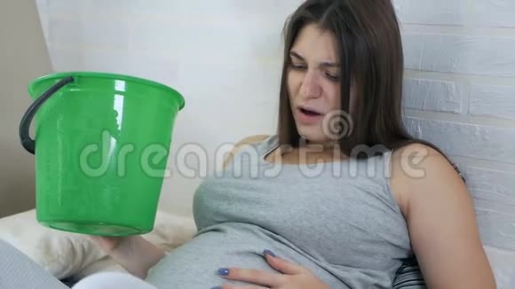 晨吐年轻的孕妇躺在沙发上吐在桶里妊娠中毒视频的预览图