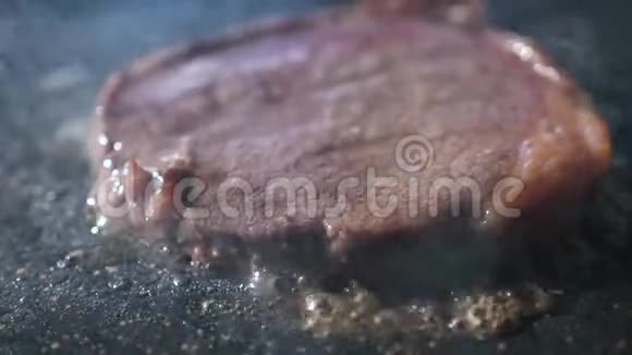 烧烤牛排关闭用火钳在烤肉上煮牛肉来翻牛排准备食物和烹饪视频的预览图