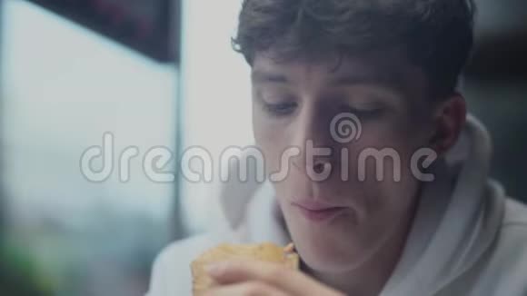 在快餐店吃三明治的有魅力有思想的年轻人的画像视频的预览图