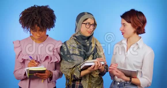 非洲欧洲和穆斯林学生带着书在蓝色背景下学习非洲妇女注销视频的预览图