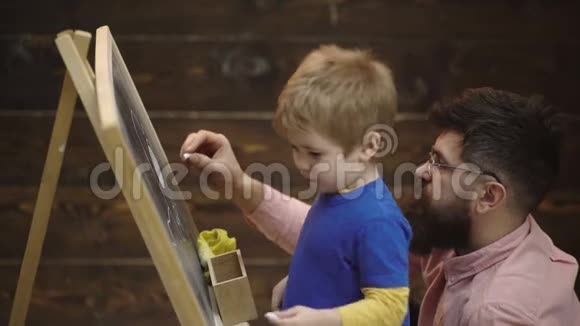 父子俩在黑板上用粉笔画小男孩和父亲的侧视图用粉笔画图片视频的预览图