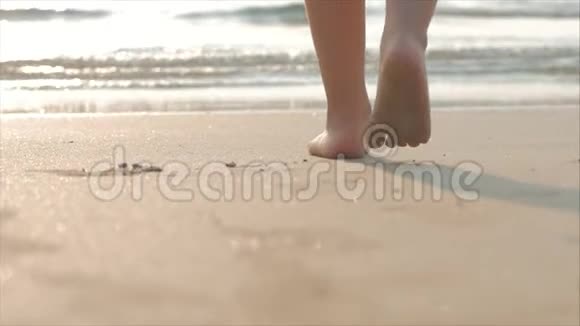 在热带海洋背景下的热带海滩上孩子们脚在湿沙上行走的剪影概念视频的预览图