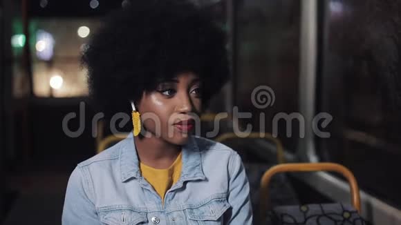 非裔美国妇女看着相机微笑着坐在公共交通工具斯特迪卡姆拍摄特写镜头城市视频的预览图