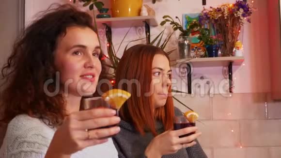 在一个节日的聚会上手里拿着一杯覆盖着酒的女孩们互相交流视频的预览图