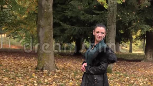 秋天公园穿黑色长夹克的漂亮女孩视频的预览图