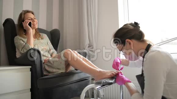 美丽的女人在水疗美容沙龙获得专业教育师父正在清洗她的指甲客户正在谈视频的预览图