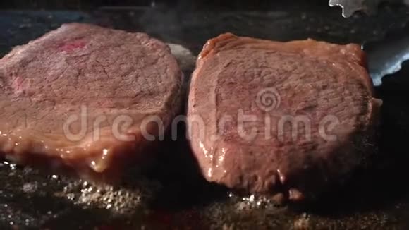 烧烤牛排关闭用火钳在烤肉上煮牛肉来翻牛排准备食物和烹饪视频的预览图