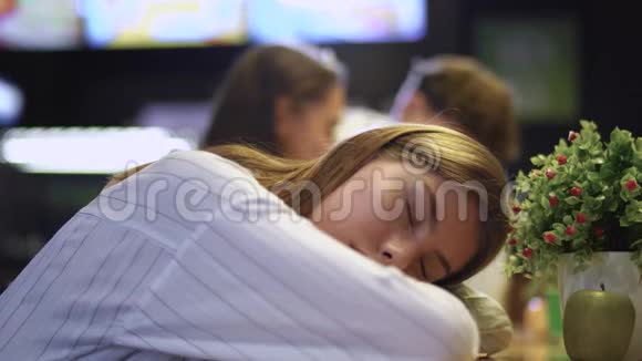 一个年轻女孩靠在咖啡馆的桌子上睡觉一个年轻的女孩在一家健康食品咖啡馆里睡觉视频的预览图