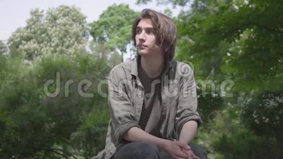 孤独紧张的年轻人坐在公园的长凳上等他的朋友或女朋友他在准备视频的预览图