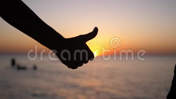 在海滩的夕阳背景下竖起大拇指视频的预览图